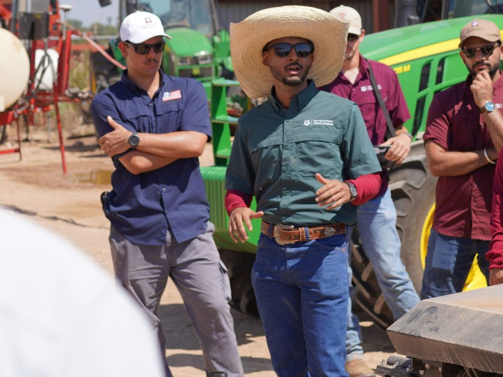 Speaking to a group beside farm equipment